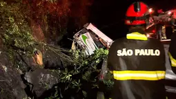 Petugas pemadam kebakaran dikerahkan di lokasi kecelakaan bus yang hilang kendali dan terjun bebas ke jurang di negara bagian Sao Paulo, Brasil, Kamis (9/6). Menurut laporan media lokal, sopir bus termasuk dalam deretan korban tewas. (RECORD TV/AFP)