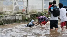 Seorang lelaki membantu membangunkan wanita yang terperosok ke dalam lubang saat banjir di kawasan Bukit Duri, Jakarta, Selasa (21/2). Salah satu bahaya banjir ialah tidak terlihatnya lubang yang bisa menyebabkan kecelakaan. (Liputan6.com/Yoppy Renato)