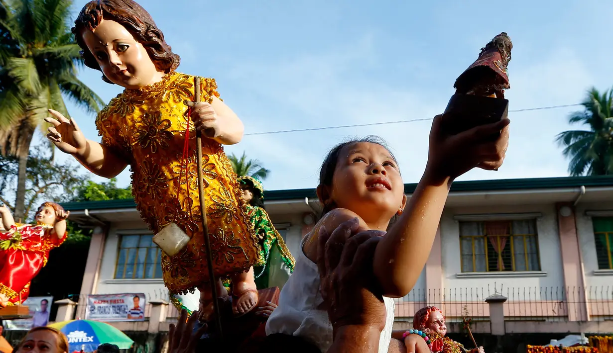 Seorang anak memegang patung simbol Bayi Yesus saat pemberkatan di Manila, Filipina (21/1). Prosesi keagaman tersebut merupakan bagian dari perayaan Santo Nino. (AP Photo / Bullit Marquez)