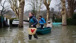 Seorang wanita menggunakan perahu membawa anak-anak di sebuah jalan banjir di Villennes sur Seine, sebelah barat Paris, (30/1). Sejumlah perjalanan kapal pesiar juga tergangu akibat hujan deras yang membuat sungai meluap. (AP Photo / Thibault Camus)