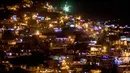 Pemandangan Comuna 13 selama perayaan Hari Lilin Kecil di Medellin, Kolombia (7/12). Warga juga mengunjungi pemakaman untuk menghiasi kuburan keluarga mereka yang tiada dengan bunga, lentera dan lilin. (AFP Photo/Luis Robayo)