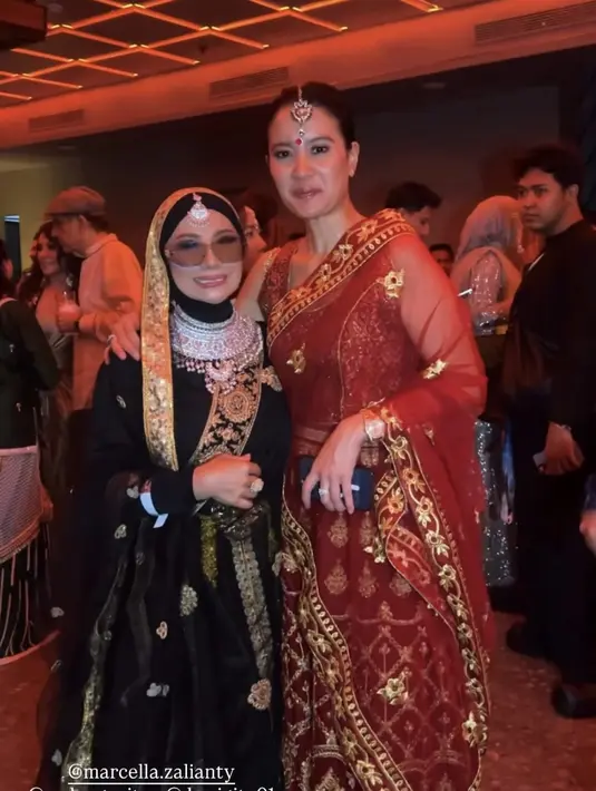 Marcella Zalianty tampil mengenakan lehenga merah berbordir emas, dari atasan sleeveless crop senada dengan rok panjangnya. Lengkap dengan selendang warna senada transparan. Serta hiasan kepala gold dan bindi merah. [@drgdevya]