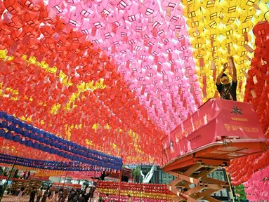 Para pekerja memasang lentera teratai di Kuil Jogyesa, Seoul, Korea Selatan, Jumat (26/5/2023). Pemasangan lentera dilakukan jelang perayaan ulang tahun Buddha pada 27 Mei. (Jung Yeon-je/AFP)