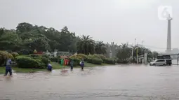 Petugas mengecek genangan air di Jalan Medan Merdeka Barat, Jakarta, Kamis (24/1/2020). Hujan deras yang mengguyur Jakarta sejak pagi tadi mengakibatkan genangan air di Jalan Medan Merdeka Barat. (Liputan6.com/Faizal Fanani)