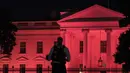 Petugas berjaga di depan Gedung Putih yang dihiasi cahaya warna pink sebagai tanda kesadaran Kanker Payudara di Washington, DC (1/10). (AFP Photo/Andrew Caballero Reynolds)