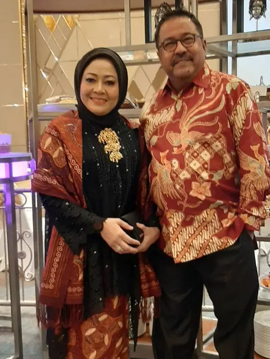 Kebaya kurung warna hitam dengan taburan beads putih, tampak kian elegan dipadukan dengan selendang merah dan bros emas. [@dewiranokarno].