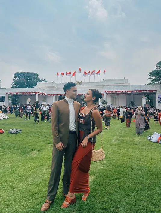 Amanda Khairunnisa kenakan dress tenun nuansa oranye-coklat saat hadiri upacara di Istana Merdeka bersama sang suami yang tampil dengan setelan jas coklatnya. [@akhairunnisa].