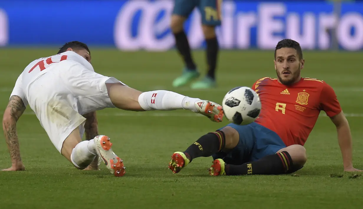 Gelandang Swiss, Steven Zuber, berebut bola dengan gelandang Spanyol, Koke, pada laga persahabatan di Stadion La Ceramica, Vila-real, Minggu (3/6/2018). Kedua negara bermain imbang 1-1. (AFP/Jose Jordan)