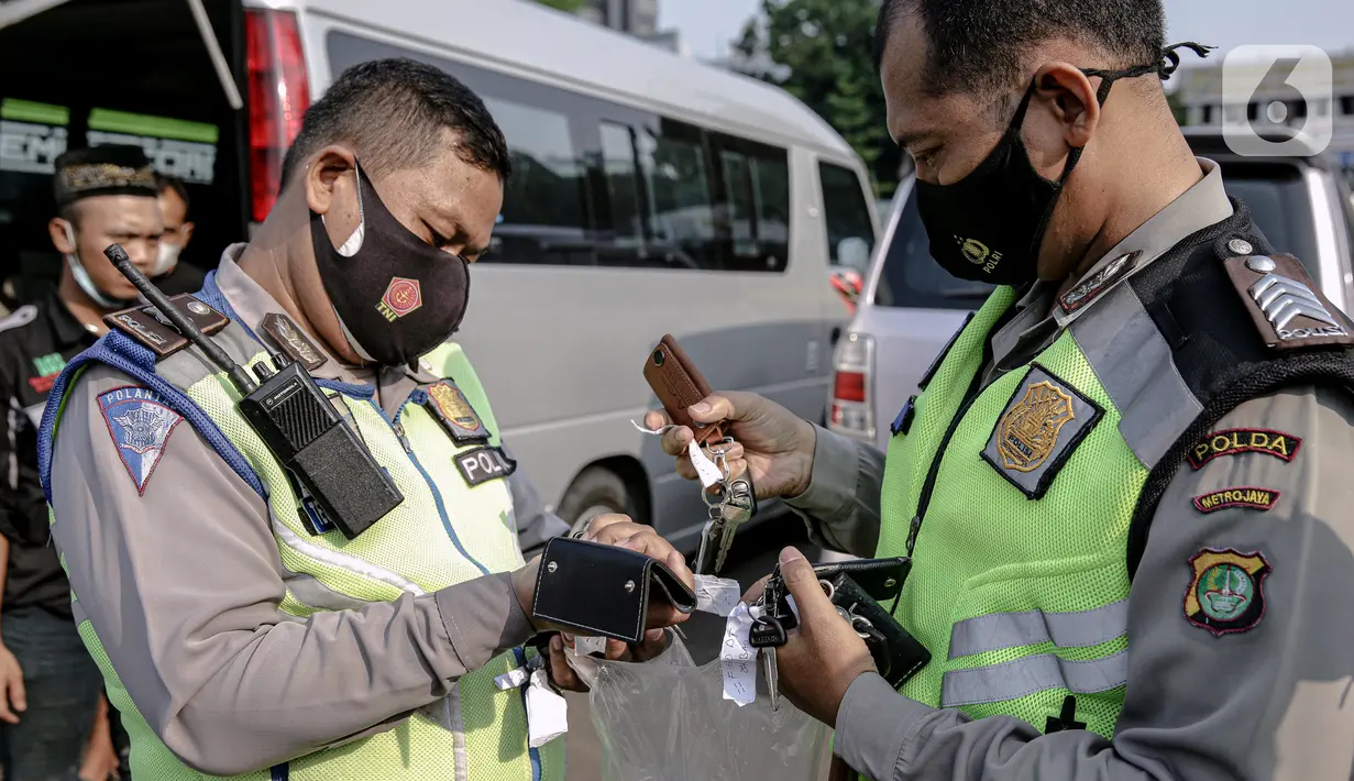 Polisi mengumpulkan kunci kendaraan travel gelap yang disita jajaran Direktorat Lalu Lintas Polda Metro Jaya, Jakarta, Kamis (29/4/2021). Sebanyak 115 kendaraan travel gelap diamankan karena diduga kuat mengangkut pemudik di tengah masa pengetatan larangan mudik 2021. (Liputan6.com/Faizal Fanani)