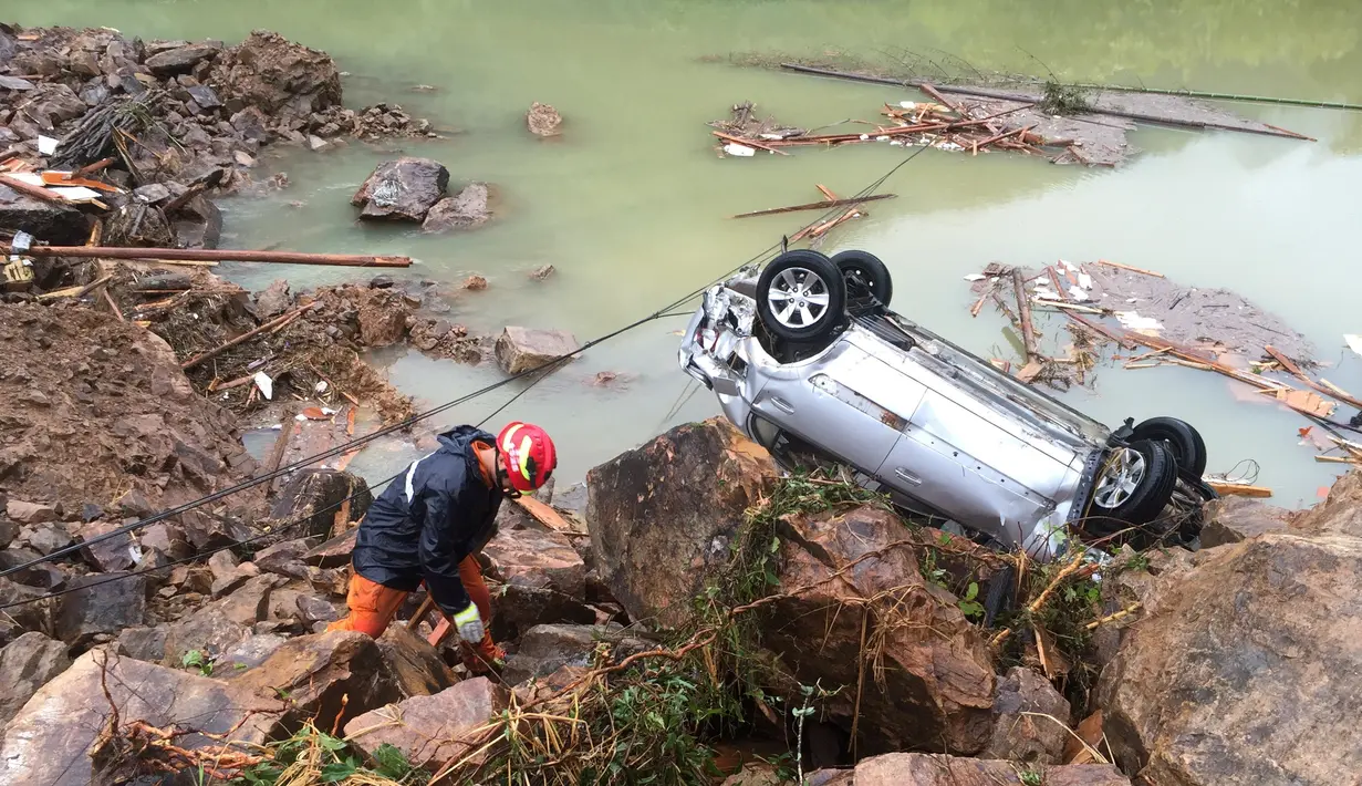 Seorang petugas berada di sebelah mobil yang terbalik di lokasi tanah longsor yang disebabkan oleh hujan deras yang dibawa oleh Topan Megi, di Sucun Village, Lishui, provinsi Zhejiang, Tiongkok, (29/9). (REUTERS/Stringer)