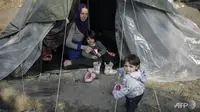 Seorang wanita Suriah duduk di tendanya bersama anak-anaknya di kamp pengungsian Vial, di pulau Chios, Yunani, yang penuh sesak dengan 5.000 orang. (AFP/Louisa Gouliamaki)