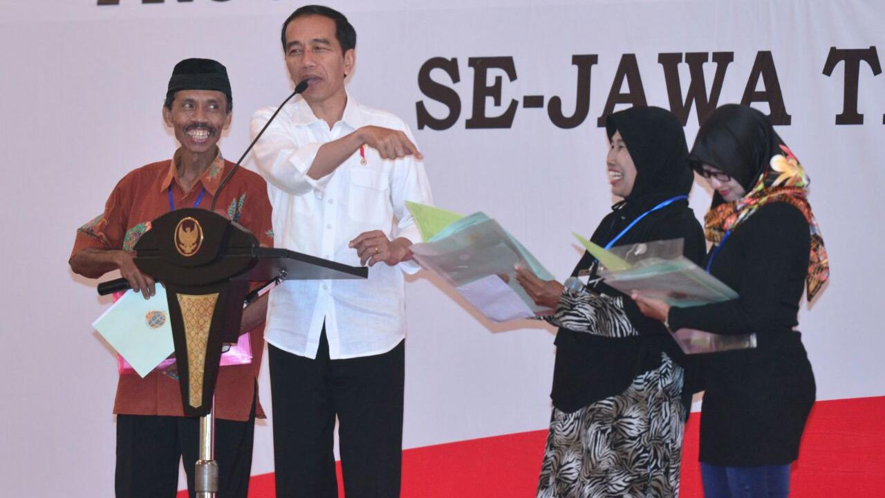 Jokowi menyerahkan sertifikat hak atas tanah program strategis nasional di Gedung New Sari Utama Convention Hall, Jember.