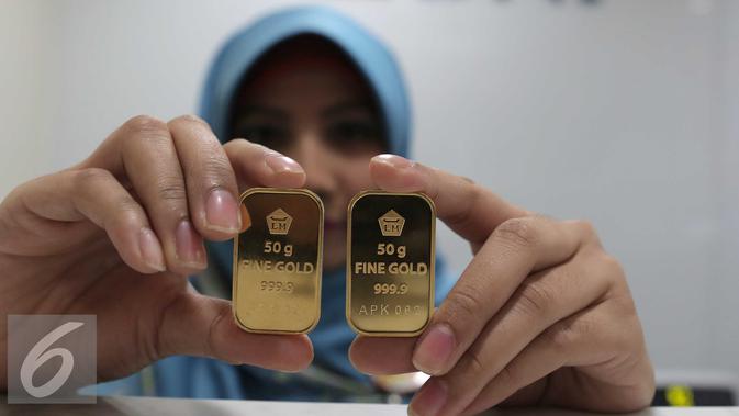 Petugas menunjukan emas batangan di kantor BNI Syariah, Jakarta, Senin (30/11). Harga jual-beli kembali (buyback) emas Antam turun Rp 1.000 usai akhir pekan kemarin naik di tengah turunnya harga emas global. (Liputan6.com/Angga Yuniar)