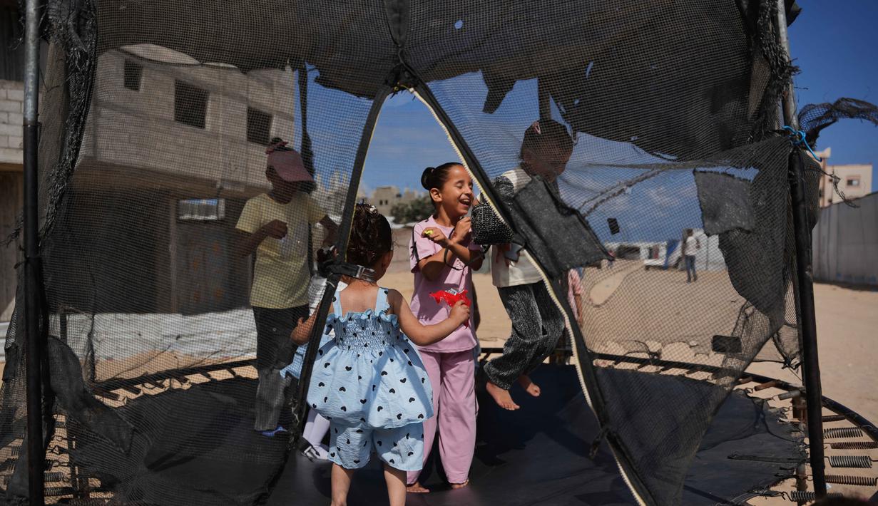 Anak-anak pengungsi Palestina bermain trampolin di sebuah kamp tenda selama Hari Raya Idul Adha di Khan Younis, Jalur Gaza, Rabu 27 Mei 2026. (AP Photo/Abdel Kareem Hana)