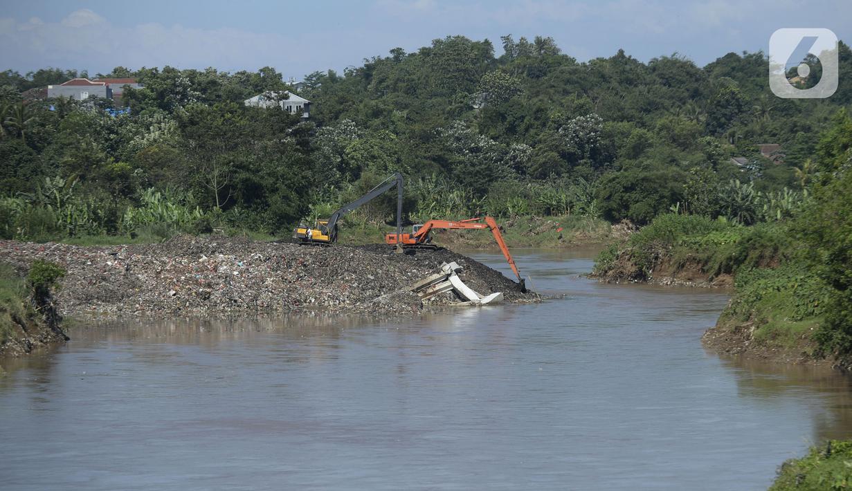 Pekerja menggunakan alat berat mengeruk sampah yang longsor di TPA Cipeucang, Serpong, Tangerang Selatan, Banten, Sebtu (23/5/2020). Turap penahan sampah TPA Cipeucang longsor pada 22 Mei 2020 dan hampir menutupi aliran Sungai Cisadane yang berada di sebelahnya. (merdeka.com/Dwi Narwoko