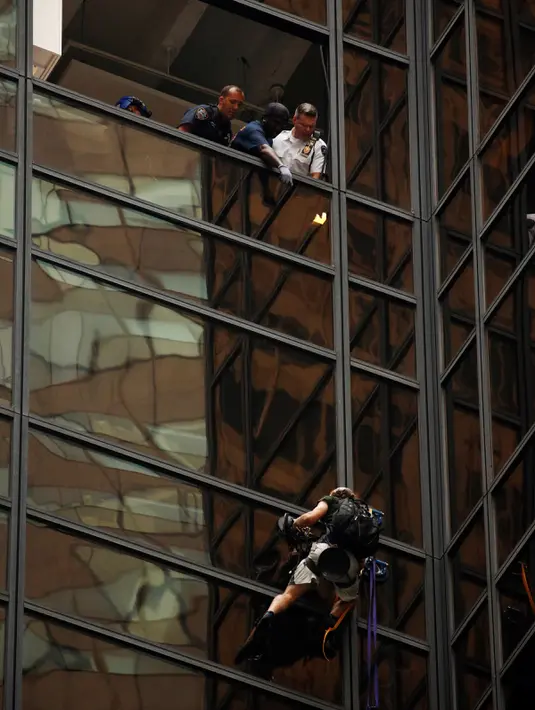 Sejumlah petugas NYPD menunggu seorang pria yang memanjat gedung Trump Tower sebelum bersiap-siap menahannya di New York, AS, Rabu (10/8). Petugas berhasil menangkap si pria berambut gondrong itu ketika mencapai lantai 21. (REUTERS/Lucas Jackson)