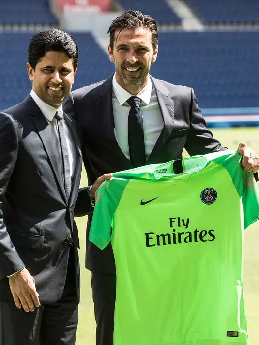 Kiper anyar PSG, Gianluigi Buffon berpose bersama Ketua klub dan CEO Paris Saint-Germain, Nasser Al Khelaifi sambil memegang jersey PSG saat resmi diperkenalkan sebagai pemain baru di stadion Parc des Princes, Paris, Senin (9/7). (AP/Jean-Francois Badias)