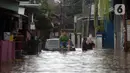 Warga duduk di atas mobil saat banjir merendam jalan dan rumah di RT 003/05, Pejaten, Jakarta, Sabtu ( 20/2/2021). Curah hujan yang tinggi sejak malam hingga dini hari mengakibatkan sejumlah kawasan terendam banjir. (merdeka.com/Imam Buhori)