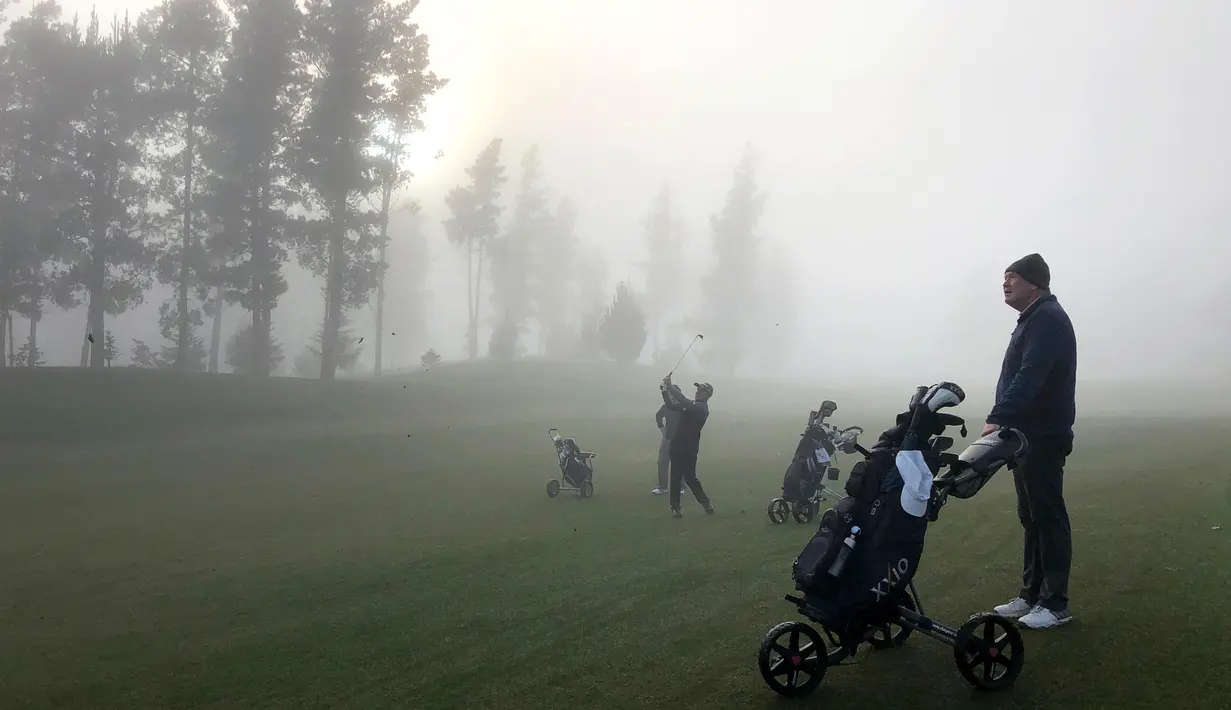 Seorang pegolf memukul bola saat bermain dalam kabut tebal di Lapangan Golf Russley di Christchurch, Selandia Baru, Sabtu (25/5/2019). Beberapa penerbangan di Bandara Christchurch ditunda atau dibatalkan karena kabut tebal menyelimuti kota tersebut. (AP Photo/Mark Baker)