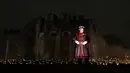 Yeoman Warders atau 'Beefeaters' berdiri di antara ribuan lilin di parit kering Tower of London, Inggris, Selasa (6/11). Nyala lilin membentuk instalasi yang disebut 'Beyond the Deepening Shadow: The Tower Remembers'. (AP Photo/Alastair Grant)