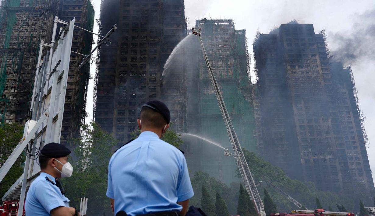 Sedikitnya 44 orang tewas, sementara 45 lainnya berada dalam kondisi kritis di berbagai fasilitas medis. Tampak dalam foto, petugas polisi berjaga di lokasi kebakaran yang terjadi pada hari Rabu di Wang Fuk Court, sebuah kompleks perumahan di distrik Tai Po, Wilayah Baru Hong Kong, Kamis 27 November 2025. (AP Photo/Chan Long Hei)