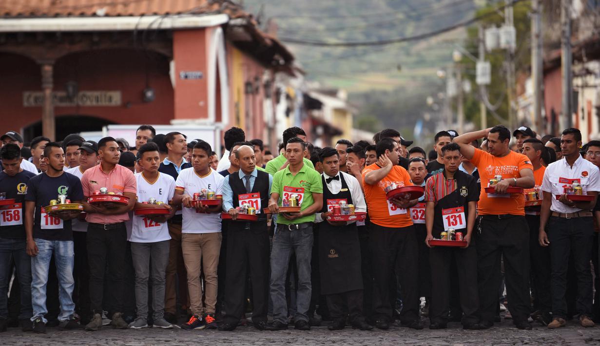 Pramusaji dari berbagai restoran bersiap mengikuti Waiters Race ke-16 di Antigua, barat daya Ibu Kota Guatemala City, Rabu (14/11). Ratusan peserta beradu kecepatan sembari membawa nampan berisi dua minuman ringan, bir dan air. (JOHAN ORDONEZ/AFP)