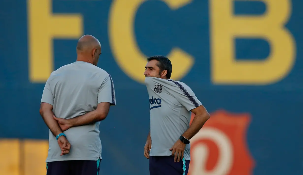 Pelatih Barcelona, Ernesto Valverde (kanan) berbincang dengan asistennya selama sesi latihan di Barcelona, Spanyol (17/9). Barcelona akan bertanding melawan PSV Eindhoven pada grup B Liga Champions di Nou Camp. (AP Photo/Manu Fernandez)