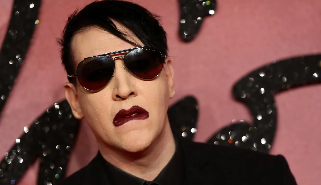 Pose Marilyn Manson saat menghidiri di Fashion Awards 2016 di London, Inggris (5/12). Mantan pacar Evan Rachel Wood tersebut tampil Fashionable dengan Jas dan kacamata hitam dengan gigi dan cincin ditangannya. (REUTERS/Neil Balai)