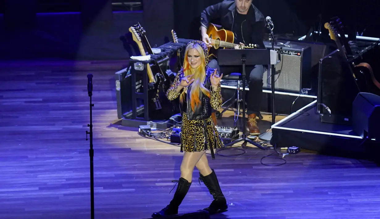 Aksi panggung Avril Lavigne  selama tampil di Academy of Country Music Honours ke-15 di Ryman Auditorium di Nashville, Tennessee pada 24 Agustus 2022. Pakaian yang dikenakan Avril terdiri dari jaket motor di atas bustier kulit hitam yang terhubung ke tudung, rok mini lipit yang serasi, pantyhose mengkilap, dan sepatu bot setinggi lutut hitam. (Mickey Bernal/Getty Images,/AFP )