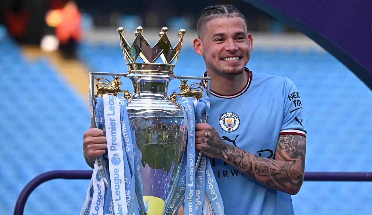 Gelandang Manchester City, Kalvin Phillips berpose dengan trofi Liga Inggris saat perayaan gelar usai laga pekan ke-37 menghadapi Chelsea di Etihad Stadium, Manchester (21/5/2023). Kalvin Phillips didatangkan pada awal musim 2022/2023 dari Leeds United. Berstatus pelapis di sektor gelandang bertahan, sejauh ini ia baru tampil 10 kali di Liga Inggris, termasuk di laga terakhir saat menang 1-0 atas Chelsea. (AFP/Oli Scarff)