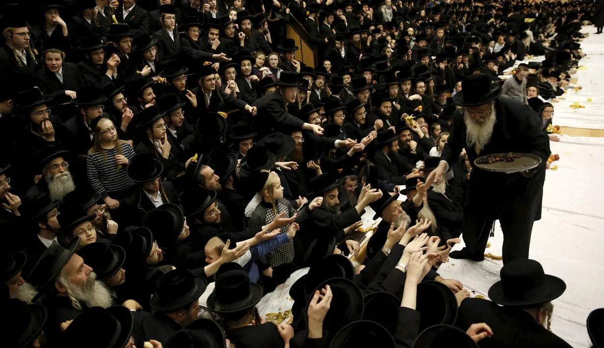Pria Yahudi Ultra-Orthodoks dari dinasti Belz Hasidic membagikan makanan pada jemaat lainnya saat perayaah Tu Bishvat, hari Arbor Yahudi, Jerusalem, (25/1). Dalam bahasa ibrani Tu Bishvat menandai tahun pohon. (REUTERS/Baz Ratner)