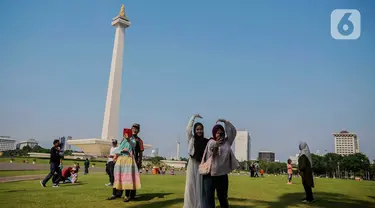 Beberapa remaja berswafoto berlatar Monumen Nasional (Monas), Jakarta, Kamis (8/2/2024). (Liputan6.com/Angga Yuniar)