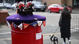 Pajangan rajutan warna merah, putih, biru dan ungu kerajaan bermunculan di kotak-kotak pos saat negara ini bersiap menyambut penobatan Raja Charles III. (Photo by Paul ELLIS / AFP)