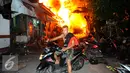 Seorang warga menyelamatkan diri dari kebakaran yang terjadi di belakang Senayan City, Jakarta, Minggu (3/7) dini hari. Sejumlah rumah semi permanen terbakar 38 mobil pemadam kebakaran dikerahkan. (Liputan6.com/Helmi Afandi)