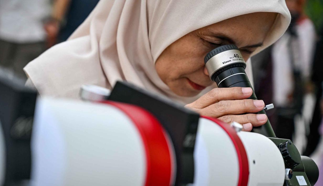 Rukyat dapat dilakukan dengan mata telanjang atau menggunakan alat bantu optik seperti teleskop dan kamera digital modern untuk meningkatkan akurasi. Rukyat berbeda dengan hisab. Tampak dalam foto, seorang wanita mengamati bulan, menjelang Idul Fitri sekaligus menandai berakhirnya bulan suci Ramadan1447 Hijriah melalui teleskop di kantor observatorium, pantai Lhoknga, Aceh pada Kamis 19 Maret 2026. (CHAIDEER MAHYUDDIN/AFP)