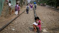 Seorang anak perempuan anak muda mengartikan buku sambil duduk di jalan (kereta api) gerobak api di New Delhi, India, Selasa (16/10). Sekitar 800 juta penghuni India hidup dalam kemiskinan. (AP Photo/Altaf Qadri)