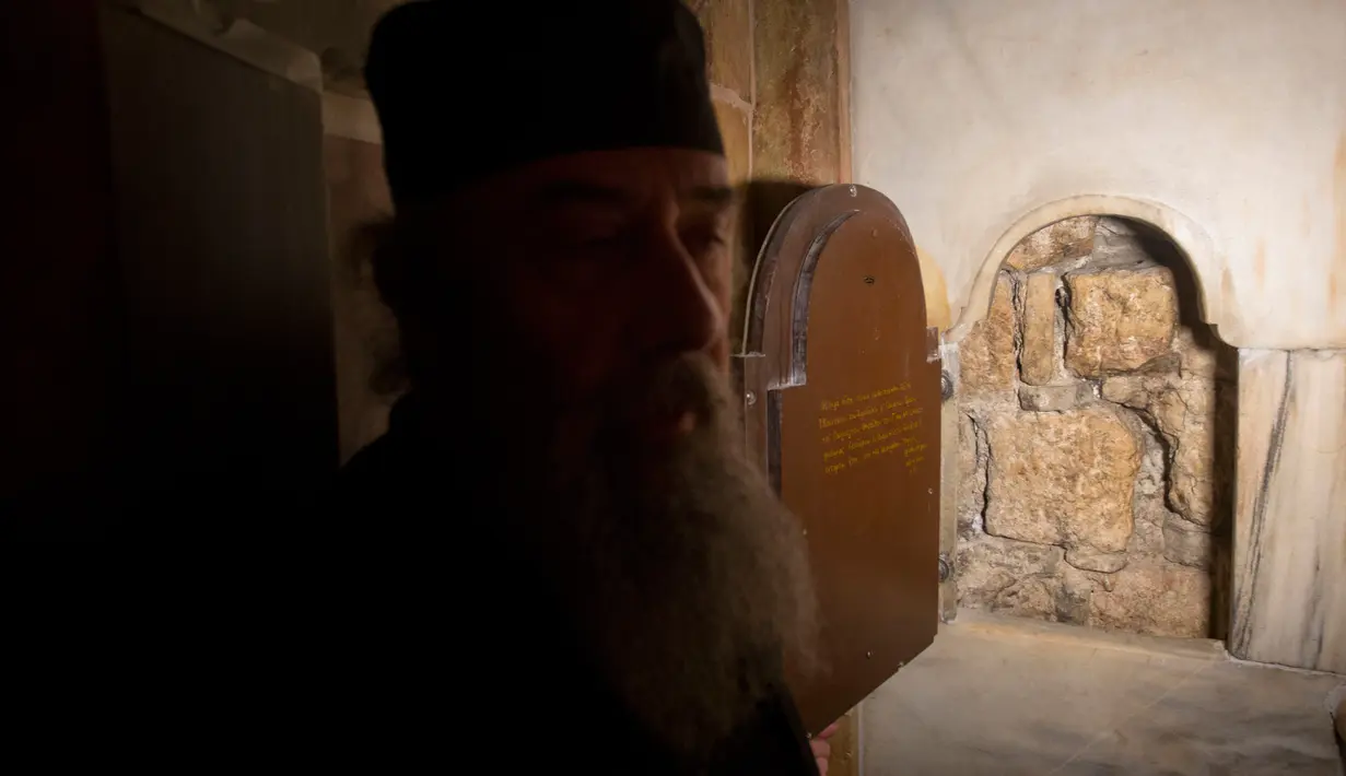 Seorang imam Yunani berdiri di dekat jendela ruang pemakaman makam Yesus di Gereja Makam Kudus di Yerusalem (20/3). Setelah tertunda selama lebih dari 200 tahun, akhirnya restorasi dan renovasi makam Yesus hampir selesai. (AP Photo/Sebastian Scheiner)