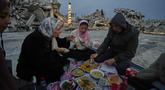 Anggota keluarga Al-Najar berbuka puasa selama bulan suci Ramadan di tengah reruntuhan bangunan yang hancur di Kota Gaza, Jumat 13 Maret 2026. Di tengah puing-puing bangunan yang nyaris rata dengan tanah, masyarakat Gaza tetap menjaga nuansa hangat kebersamaan Ramadan seperti biasanya. (AP Photo/Jehad Alshrafi)