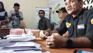 Ketua Bawaslu Pekanbaru Indra Kholid dengan uang diduga untuk serangan fajar di meja hasil tangkapan anggotanya. (M Syukur/Liputan6.com)