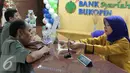 Teller tengah melayani nasabah di Bank Bukopin Syariah, Jakarta, Selasa (29/12). Namun kurs tengah Bank Indonesia mencatat rupiah menguat tipis 0,003% ke Rp 13.639 per dollar AS. (Liputan6.com/Angga Yuniar)