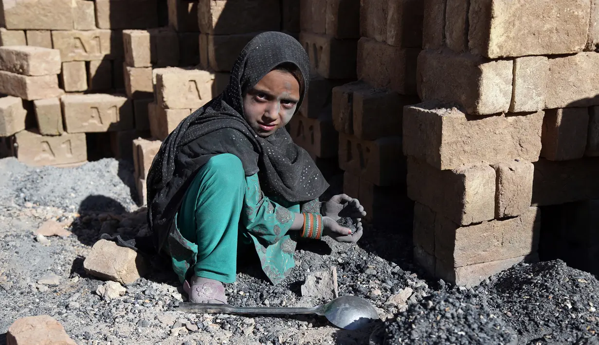 Seorang anak mengumpulkan sisa batu bara yang digunakan di pabrik batu bata di pinggiran Kabul, Afghanistan, Rabu (12/6/2019). Ribuan anak Afghanistan bekerja mencari uang untuk menghidupi keluarga mereka. (AP Photo/Rahmat Gul)