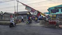 Sejumlah warga melintasi palang pintu manual KRL Rawa Geni, Kecamatan Cipayung, Kota Depok. (Liputan6.com/Dicky Agung Prihanto)