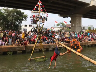 Warga mengikuti lomba jalan di atas batang pinang yang diliumuri oli di di atas aliran Kalimalang, Cipinang Melayu, Makasar, Jakarta Timur, Sabtu (19/8/2023). (Liputan6.com/Herman Zakharia)