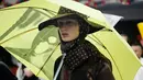 Seorang model mengenakan rancangan desainer Raf Simons dalam acara Men’s Fashion Week di New York, Selasa (11/7). Topi dan payung menjadi aksesoris andalan Raf Simons dalam rancangannya. (AP/Frank Franklin)