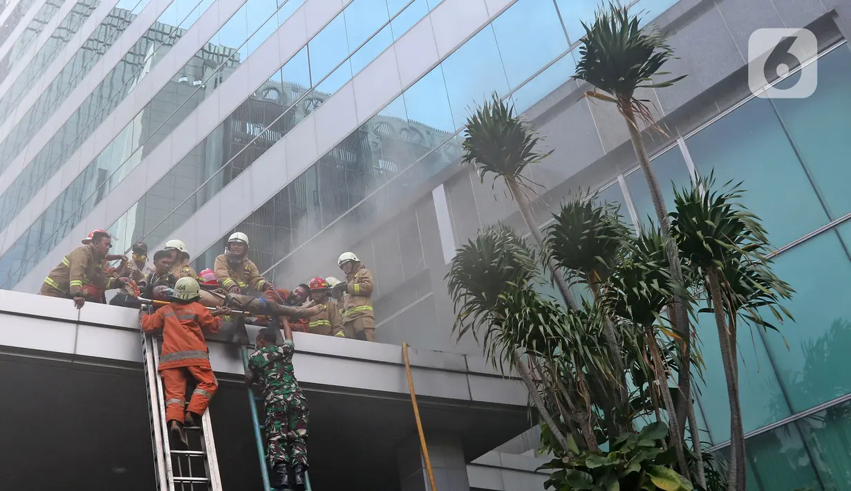 Petugas pemadam kebakaran mengevakuasi korban kebakaran di Gedung Cyber 1, Jakarta, Kamis (2/12/2021). Saat melakukan evakuasi, petugas pemadam kebakaran menemukan tiga orang dalam keadaan tak sadarkan diri di dalam gedung. (Liputan6.com/Herman Zakharia)