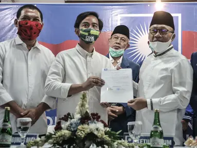 Ketua Umum PAN Zulkifli Hasan menyerahkan dokumen dukungan kepada bakal calon Wali Kota Solo Gibran Rakabuming Raka saat menggelar pertemuan di Jakarta, Rabu (12/8/2020). PAN telah resmi memberikan dukungannya kepada Gibran Rakabuming pada Pilkada Solo 2020. (merdeka.com/Iqbal Nugroho)