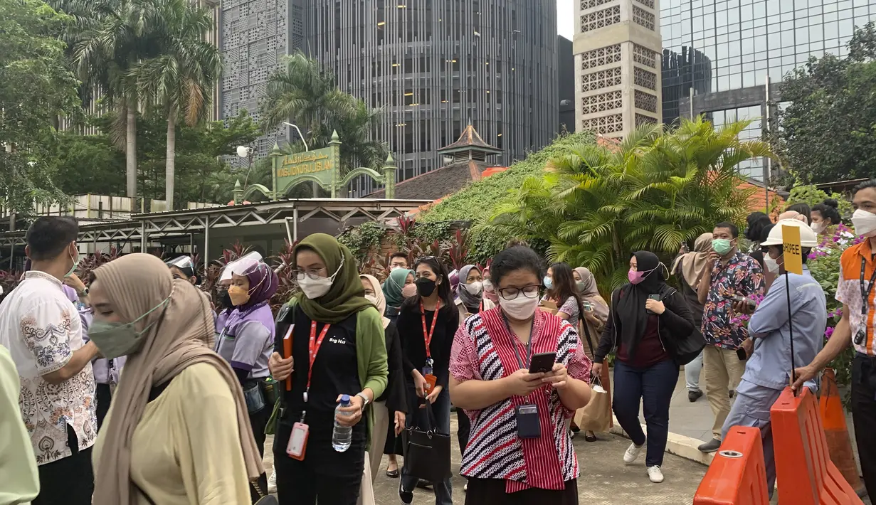 Warga menunggu di luar gedung perkantoran saat mengevakuasi diri setelah gempa mengguncang Jakarta, Jumat (14/1/2022). Gempa magnitudo 6,7 yang berpusat di Banten pada pukul 16.05 WIB membuat kepanikan di berbagai daerah. (AP Photo/Tatan Syuflana)