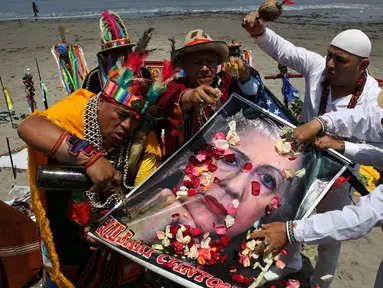 Seorang dukun Peru menyiram perasan buah pada poster bergambar Capres AS dari Partai Demokrat, Hillary Clinton saat melakukan ritual prediksi menjelang pemilihan presiden AS, di Lima, Peru, Senin (7/11). (REUTERS/Mariana Bazo)