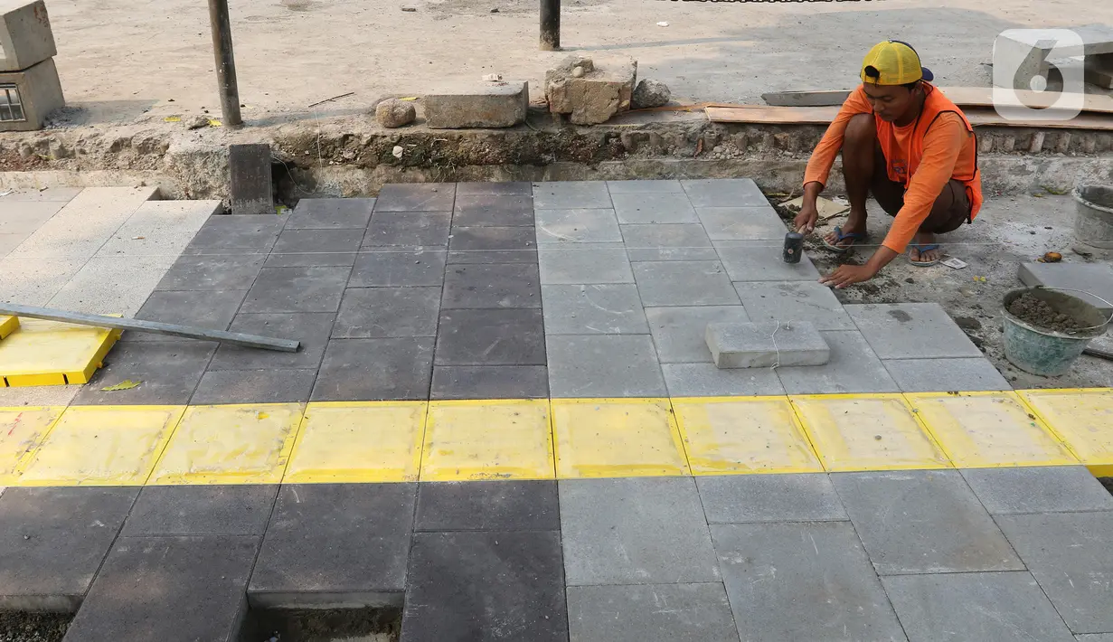 Pekerja mengerjakan proyek revitalisasi trotoar di kawasan Kemang, Jakarta Selatan, Selasa (15/10/2019). Pemerintah Provinsi DKI menargetkan pelebaran dan penataan trotoar ini akan rampung pada Desember 2019. (Liputan6.com/Herman Zakharia)