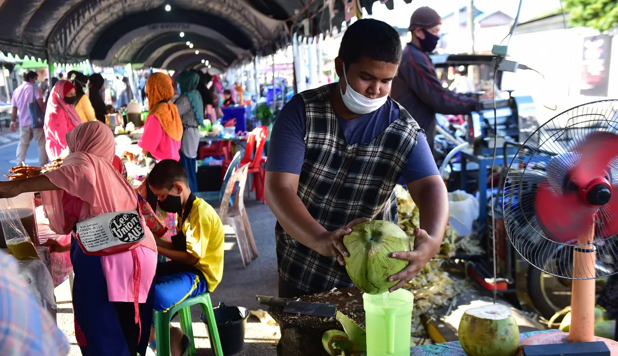 Seorang pria yang mengenakan masker menyiapkan minuman kelapa di pasar menjelang berbuka puasa selama bulan suci Ramadan di Provinsi Narathiwat, Thailand, Selasa (5/5/2020). Ramadan kali ini berlangsung di tengah bayang-bayang virus corona COVID-19. (Madaree TOHLALA/AFP)